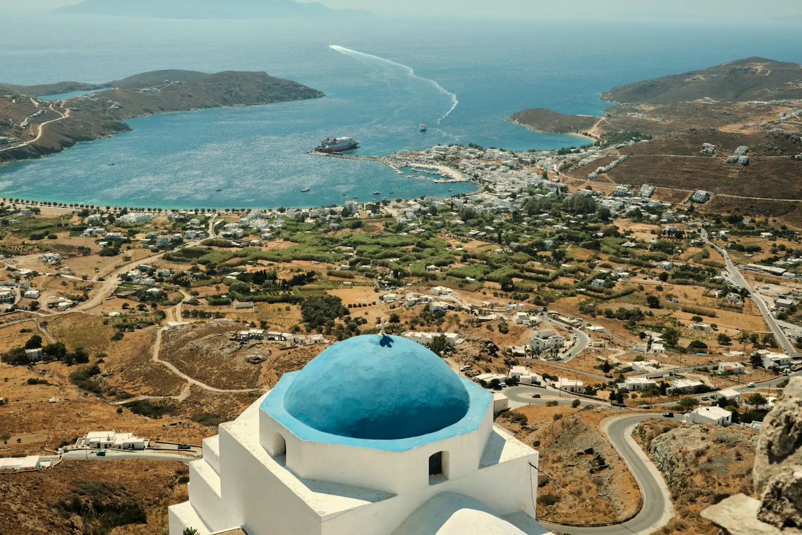 a white building with a blue dome and a blue dome on a hill overlooking a city and water