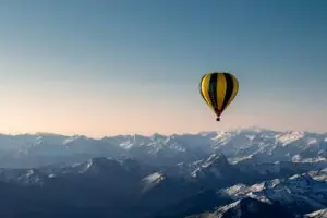 Austria yellow and blue hot air balloon flying over the mountains during daytime