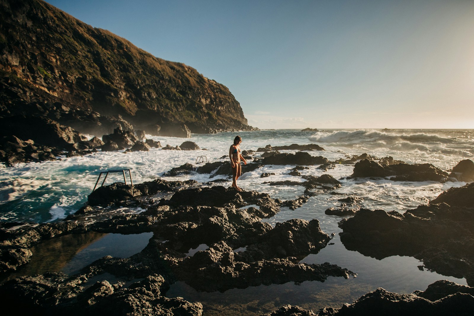 Ponta Delgada Portugal woman in white bikini standing on rocky shore during daytime