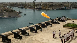 a group of people standing on a dock with cannons and a fire