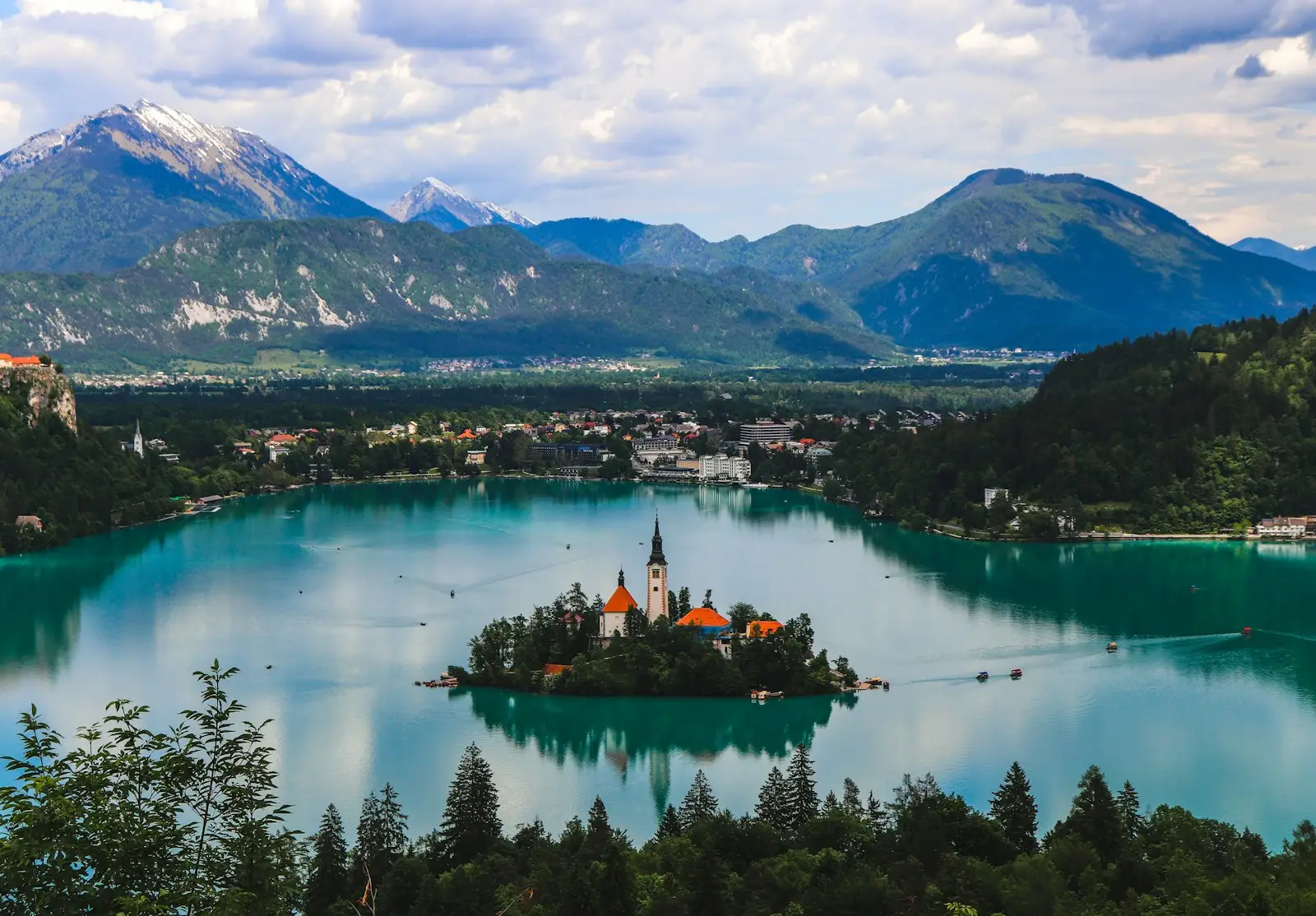 Lake Bled green trees near lake and mountains during daytime